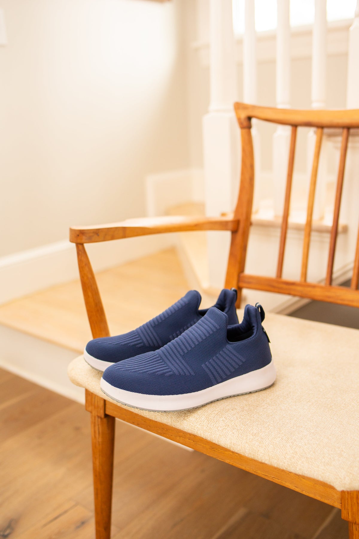 Blue slip-on sneakers on a wooden chair with a neutral background