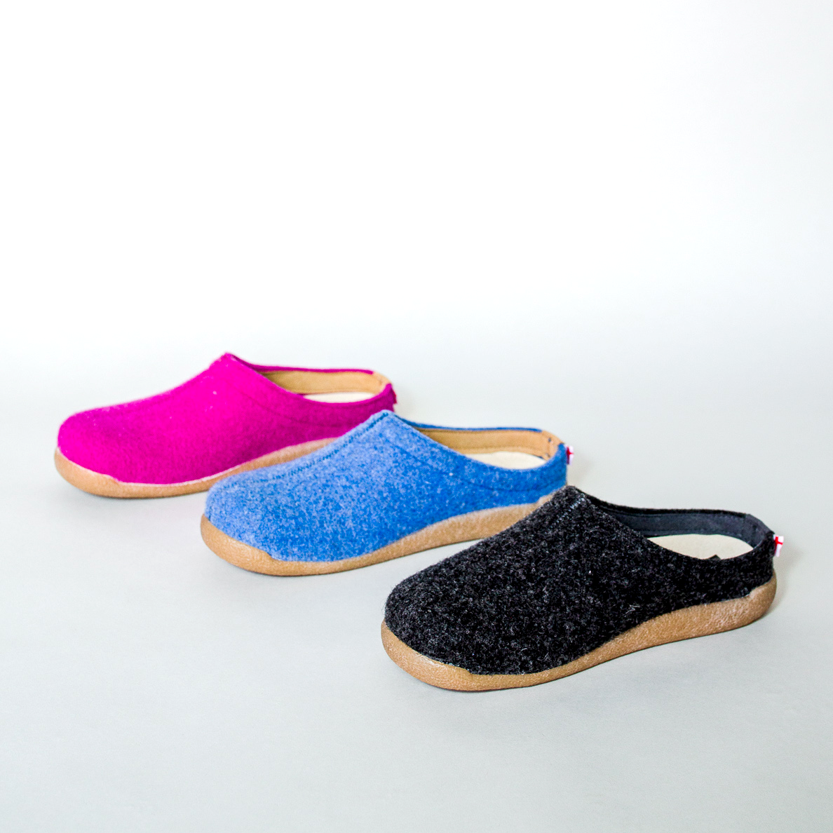 Lineup of three colors of wool slippers on grey background